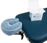 Stack of 50 clear, fitted disposable headrest covers for massage tables, neatly packed in a box.