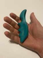 A green, thumb-shaped plastic massage tool designed for deep tissue and trigger point therapy, held in a hand.