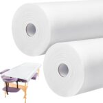 Two rolls of white disposable non-woven massage table sheets, neatly stacked and ready for use in a professional setting.
