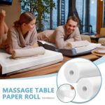 Two rolls of white disposable non-woven massage table sheets, neatly stacked and ready for use in a professional setting.