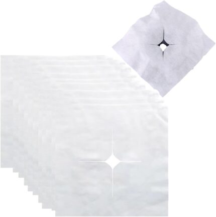 Stack of 100 white UtySty disposable face cradle covers on a massage table headrest.