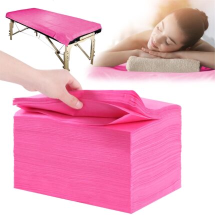 Stack of 100 individually folded pink disposable massage table sheets, made of non-woven fabric, ready for use.