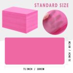 Stack of 100 individually folded pink disposable massage table sheets, made of non-woven fabric, ready for use.