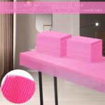 Stack of 100 individually folded pink disposable massage table sheets, made of non-woven fabric, ready for use.