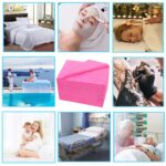 Stack of 100 individually folded pink disposable massage table sheets, made of non-woven fabric, ready for use.